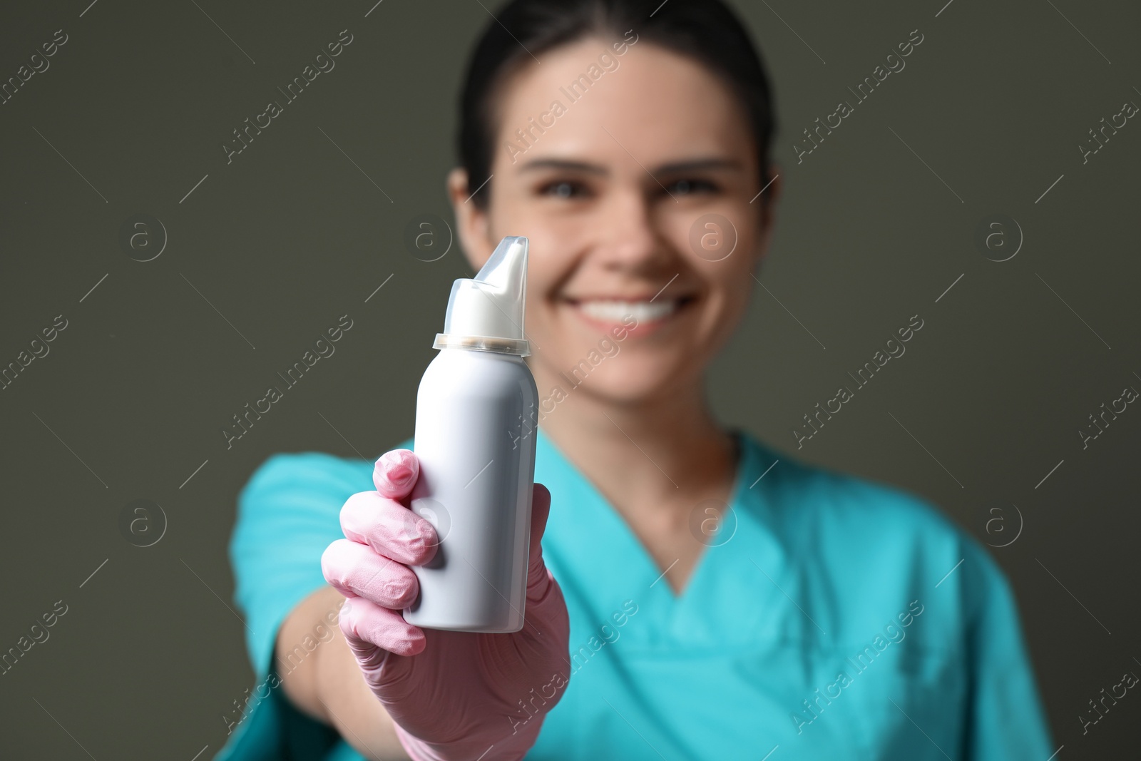 Photo of Woman holding nasal spray bottle on olive background, selective focus