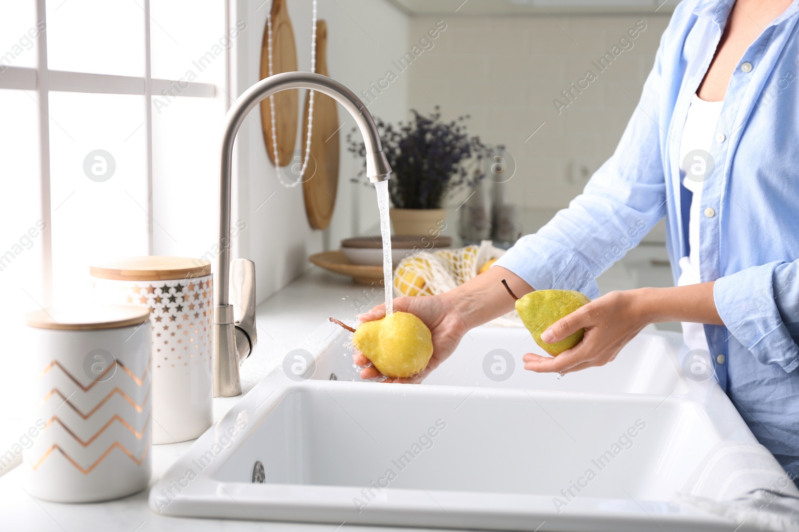 Photo of Woman washing fresh ripe pears in kitchen, closeup