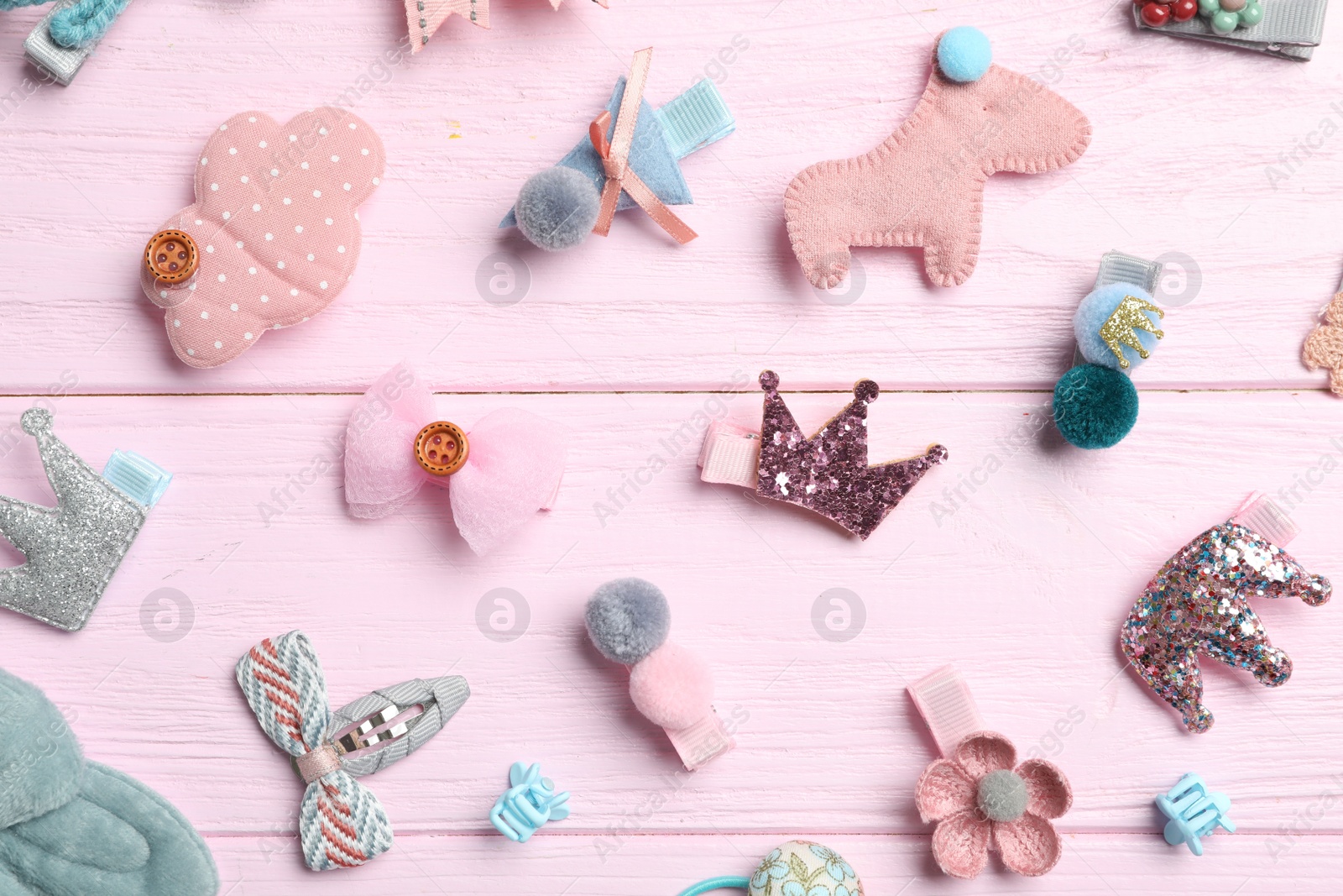 Photo of Cute hair clips on pink wooden table, flat lay