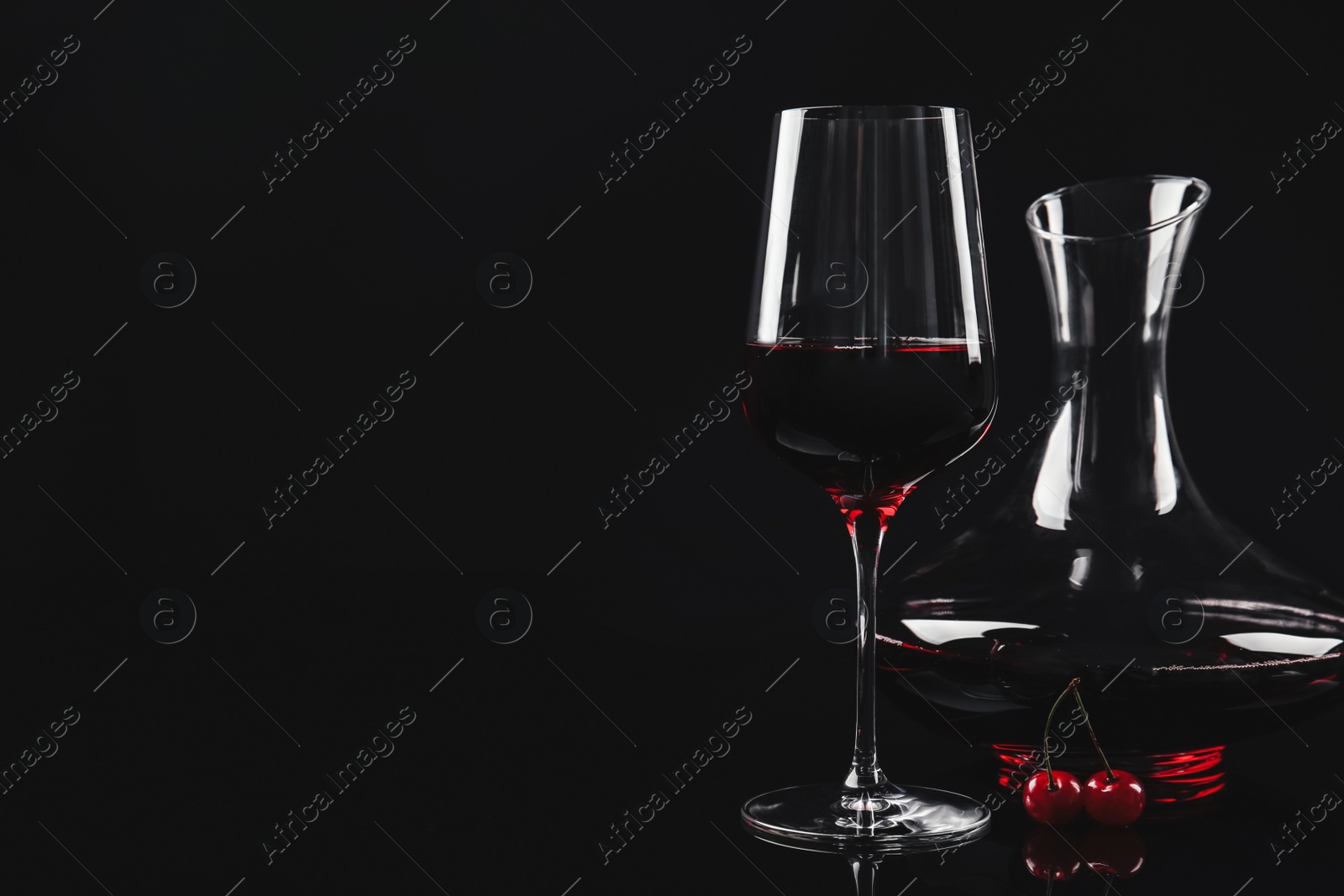 Photo of Delicious cherry wine and ripe juicy berries on black background. Space for text