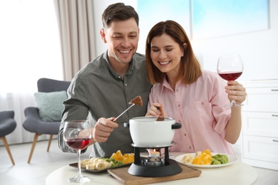 Happy couple enjoying fondue dinner at home