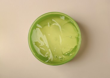Jar of aloe gel on beige background, top view