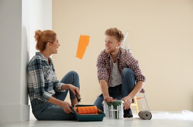 Photo of Happy couple with paint planning home repair indoors