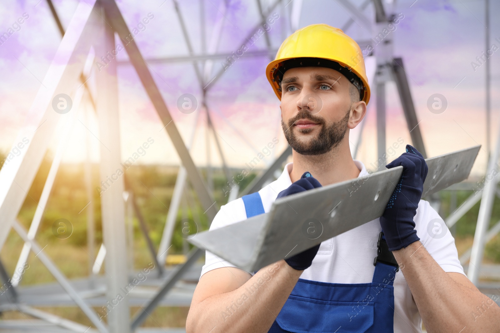 Photo of Worker with detail from high voltage tower construction on building site. Installation of electrical substation