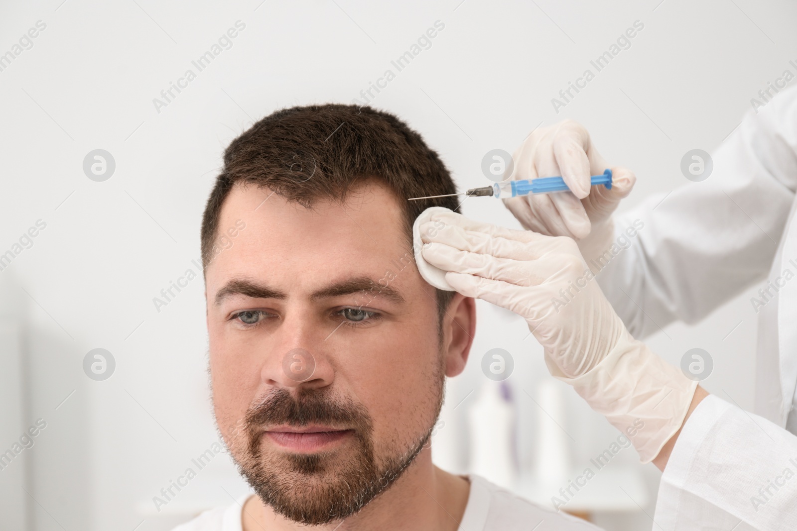 Photo of Man with hair loss problem receiving injection in salon