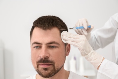 Man with hair loss problem receiving injection in salon