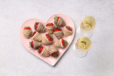 Photo of Heart shaped plate with delicious chocolate covered strawberries and sparkling wine on light table, flat lay