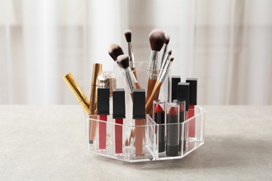 Photo of Lipstick holder with different makeup products on table indoors