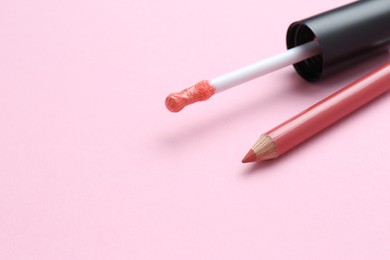 Photo of Lip pencil and brush of liquid lipstick on pink background, space for text. Cosmetic products