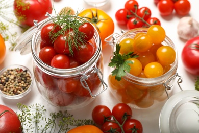 Pickling jars with fresh tomatoes on white table, closeup