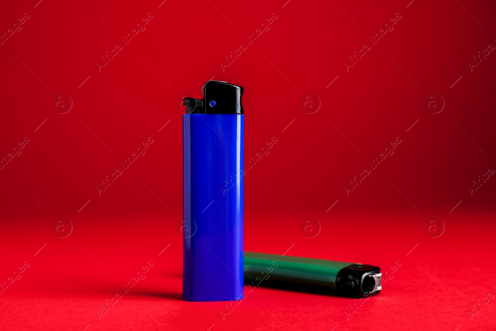 Photo of Stylish small pocket lighters on red background