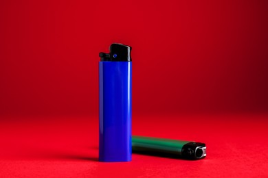 Photo of Stylish small pocket lighters on red background