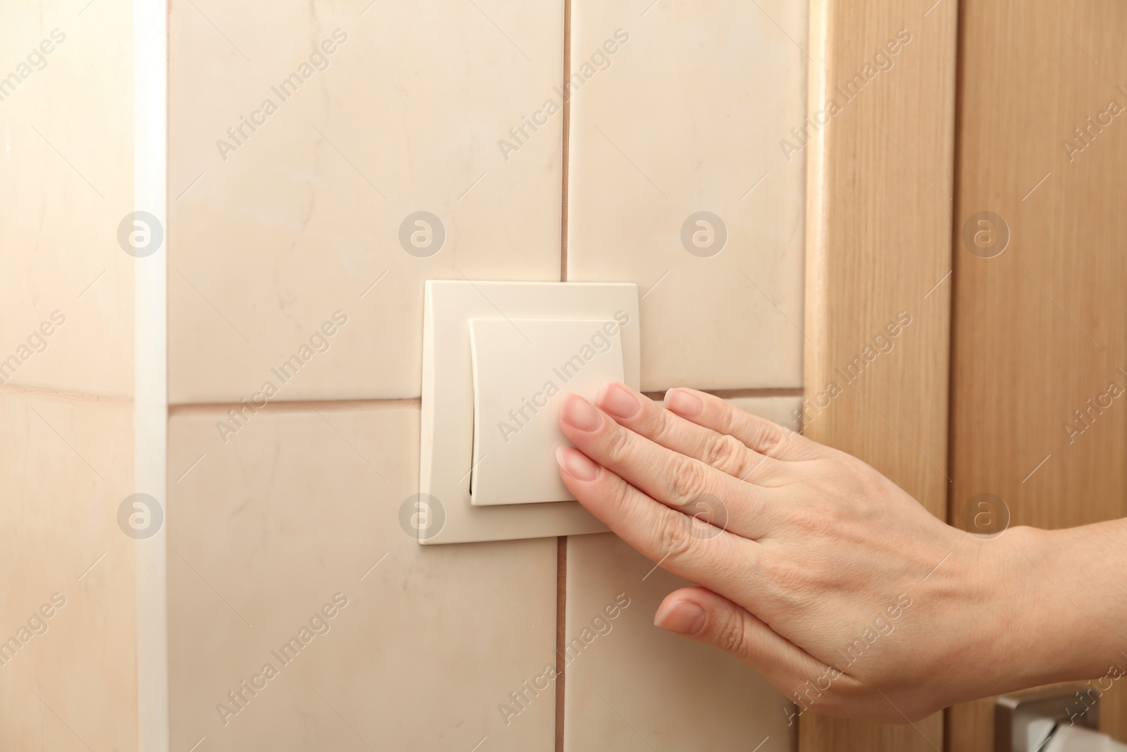 Photo of Woman pressing light switch indoors, closeup of hand