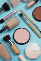 Photo of Face powders and other decorative cosmetic products on light blue background, flat lay