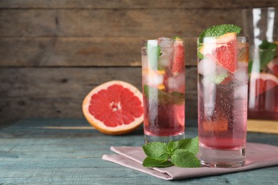 Photo of Delicious grapefruit lemonade with soda water and mint on blue wooden table, space for text. Fresh summer cocktail