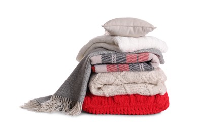 Stack of pillows and folded warm plaids on white background