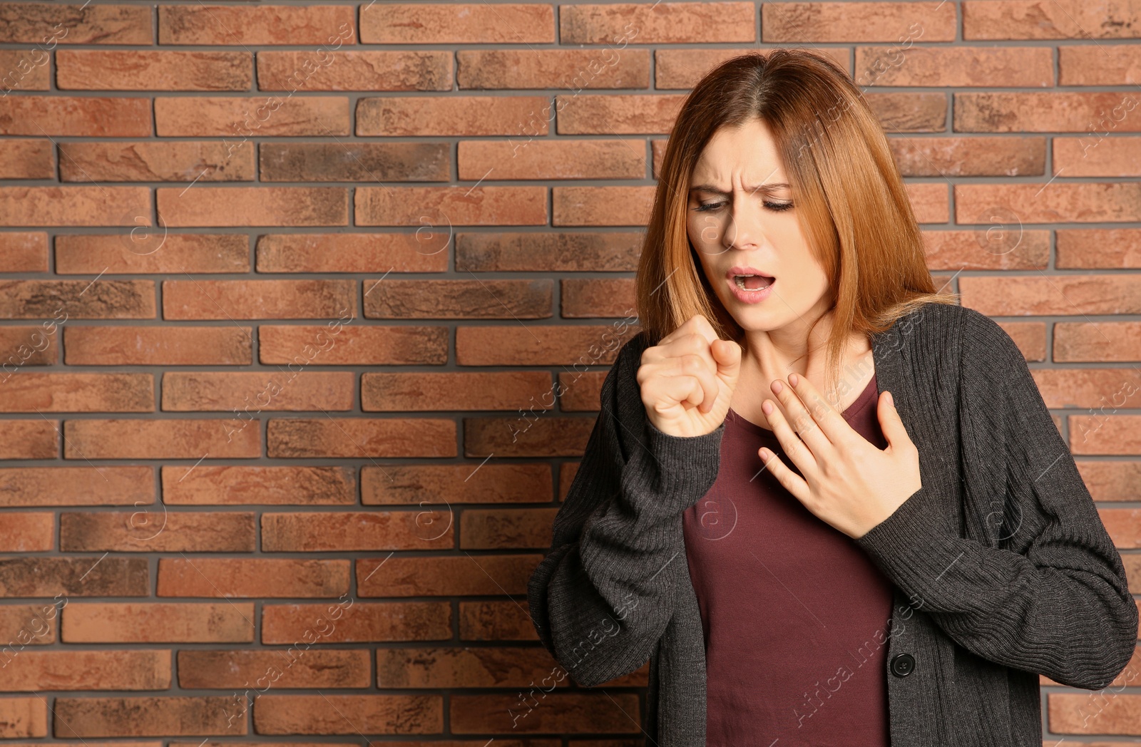 Photo of Woman suffering from cough near brick wall. Space for text
