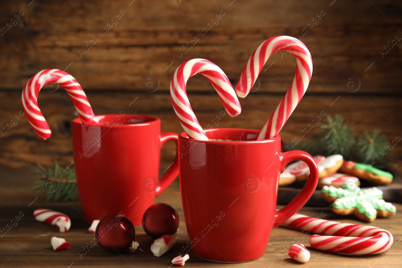 Photo of Cups of hot chocolate with candy canes and Christmas decor on wooden table