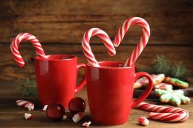 Photo of Cups of hot chocolate with candy canes and Christmas decor on wooden table