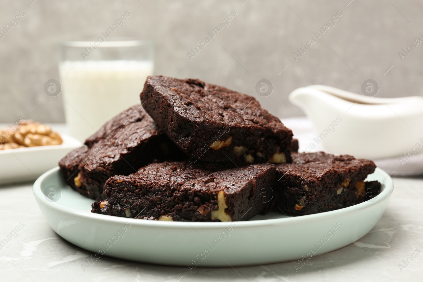 Photo of Delicious chocolate brownies with nuts on light grey table, closeup