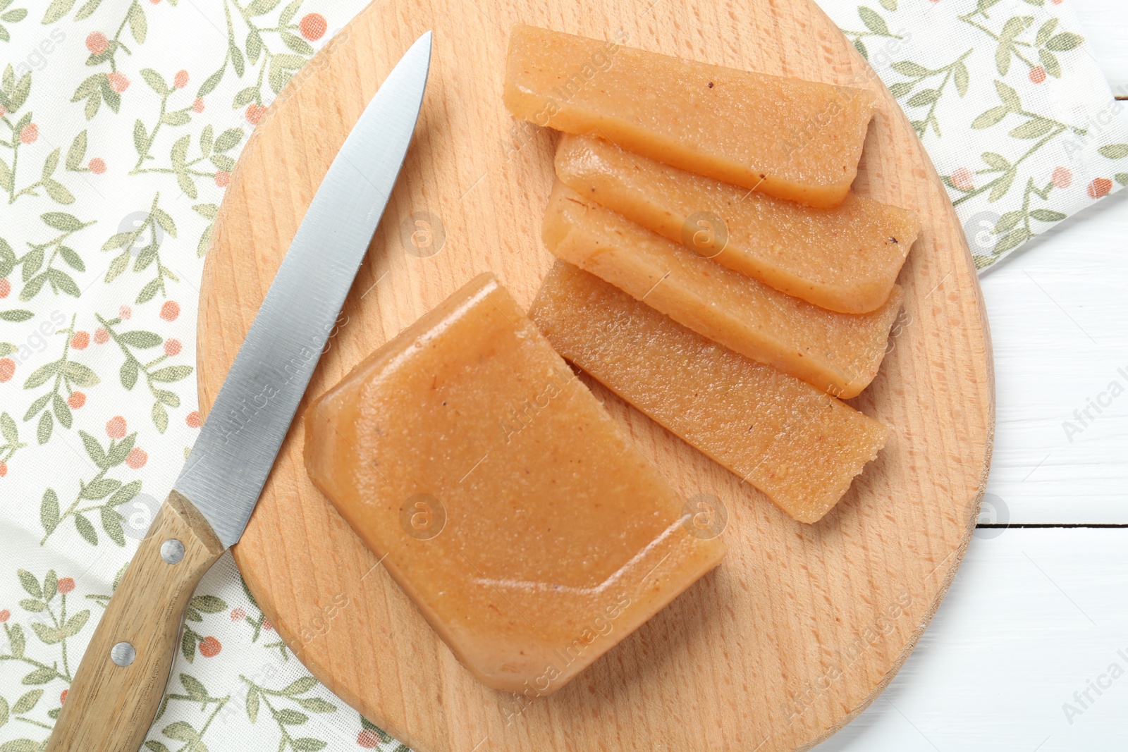 Photo of Tasty sweet quince paste and knife on white wooden table, top view