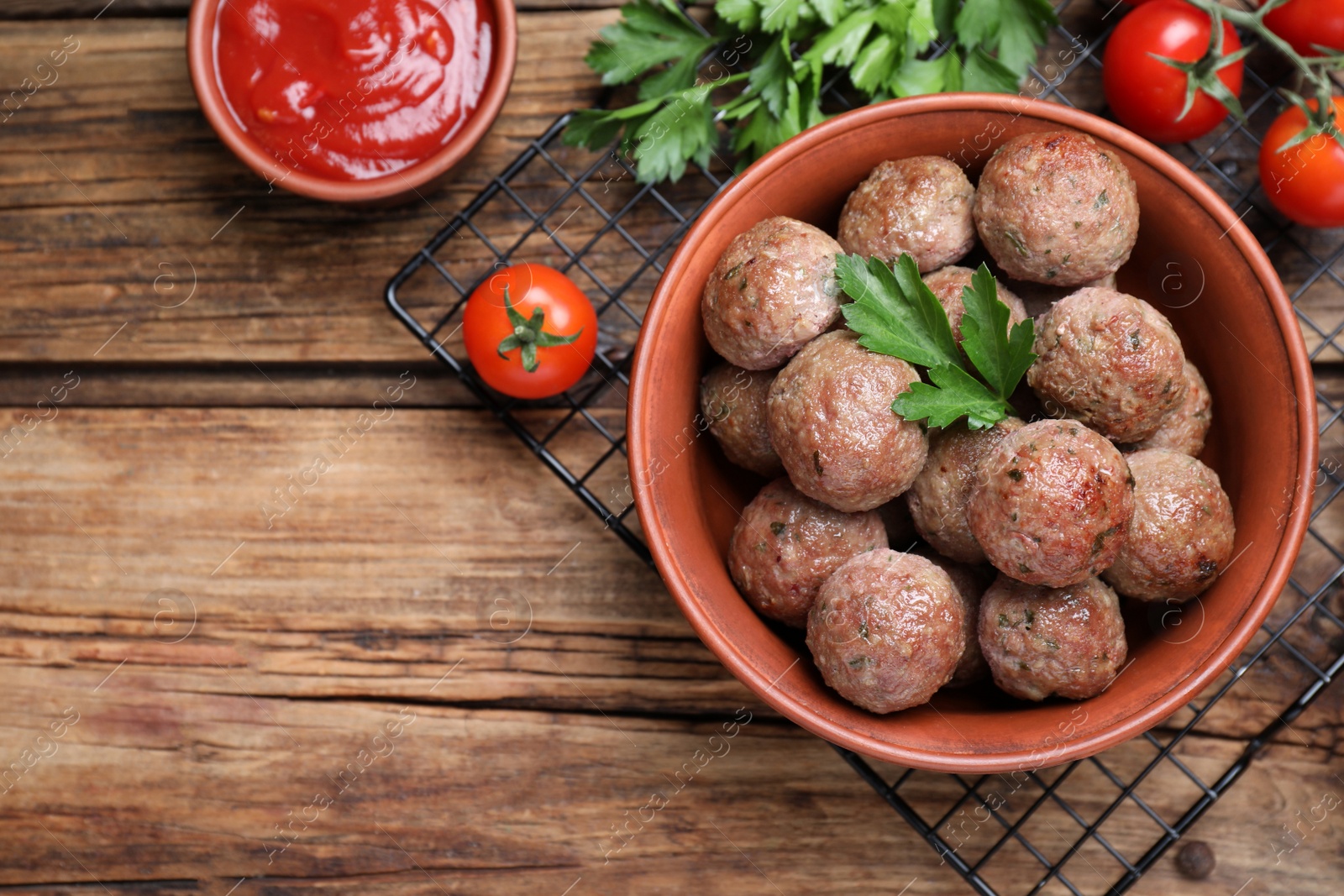 Photo of Tasty cooked meatballs with parsley on wooden table, flat lay. Space for text