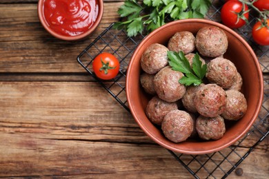Tasty cooked meatballs with parsley on wooden table, flat lay. Space for text