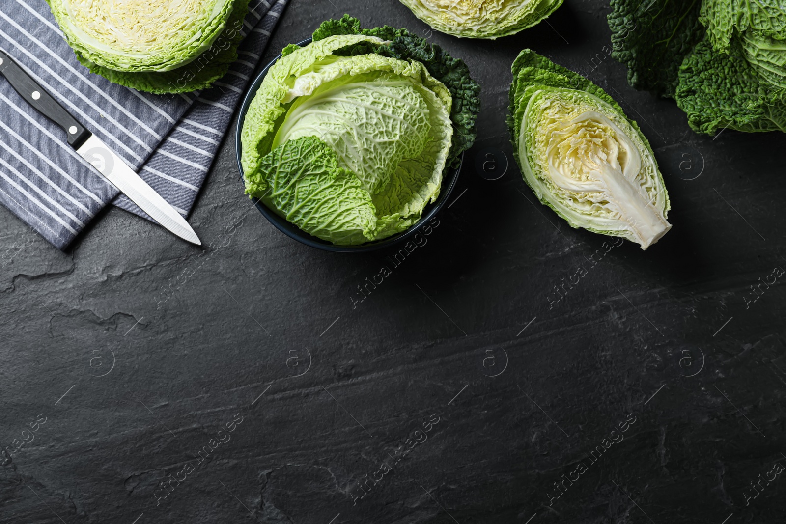 Photo of Cut fresh savoy cabbages on black table, flat lay. Space for text