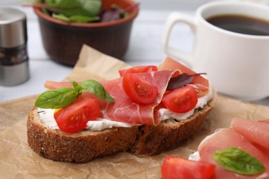 Photo of Tasty bruschetta with prosciutto, tomatoes and cheese on white wooden table, closeup