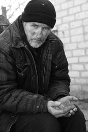 Photo of Poor homeless senior man holding coins outdoors. Black and white effect