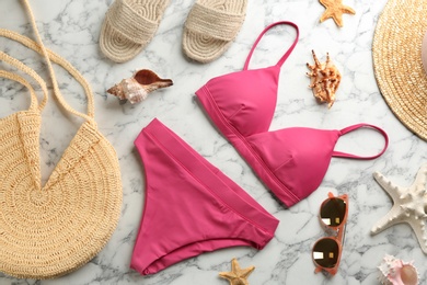 Photo of Beautiful pink bikini and beach accessories on white marble background, flat lay