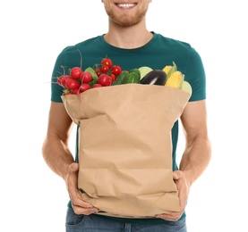 Young man with bag of fresh vegetables on white background, closeup