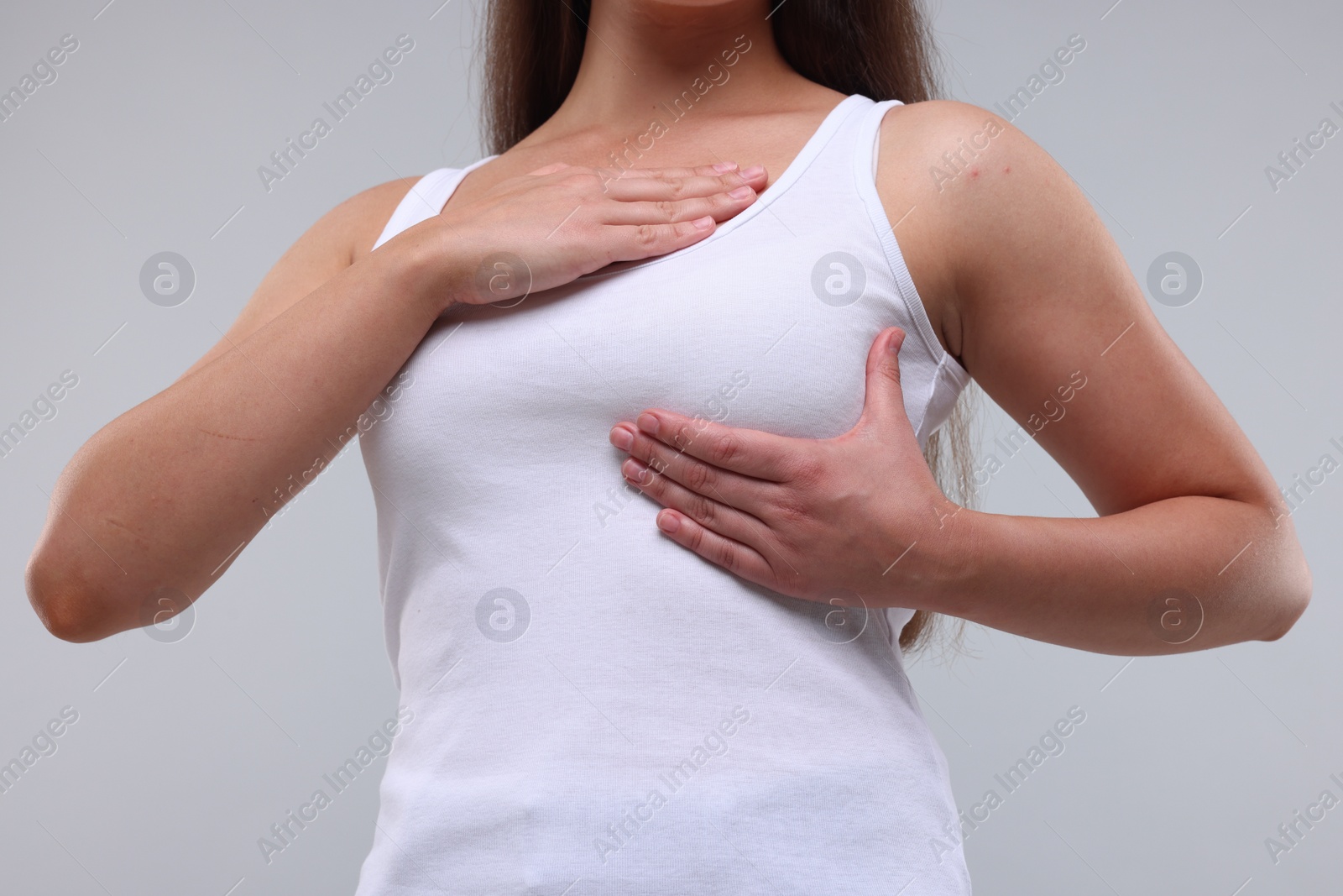 Photo of Woman doing breast self-examination on light grey background, closeup