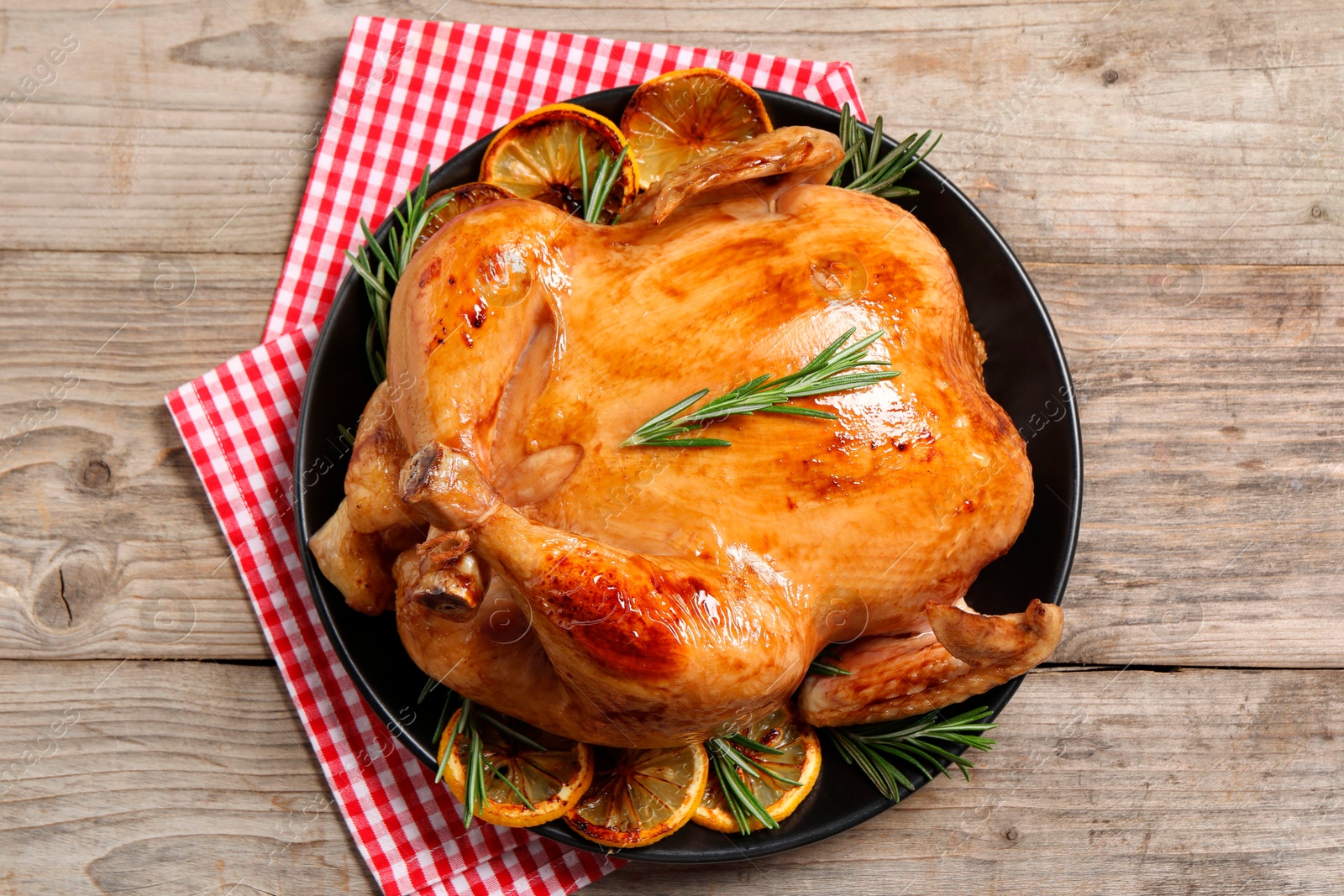 Photo of Tasty roasted chicken with rosemary and lemon on wooden table, top view