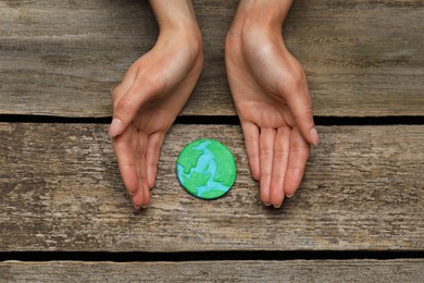 Photo of Happy Earth Day. Woman with plasticine planet at wooden table, top view
