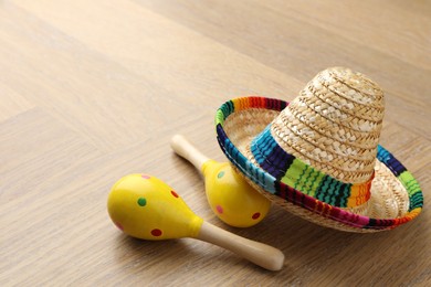 Mexican sombrero hat and maracas on wooden table. Space for text