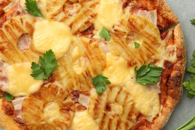 Delicious pineapple pizza with parsley on gray table, top view