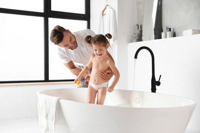 Young father with cute little daughter in bathroom