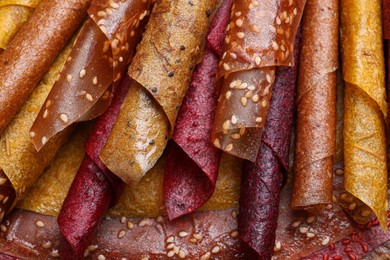 Delicious fruit leather rolls as background, top view