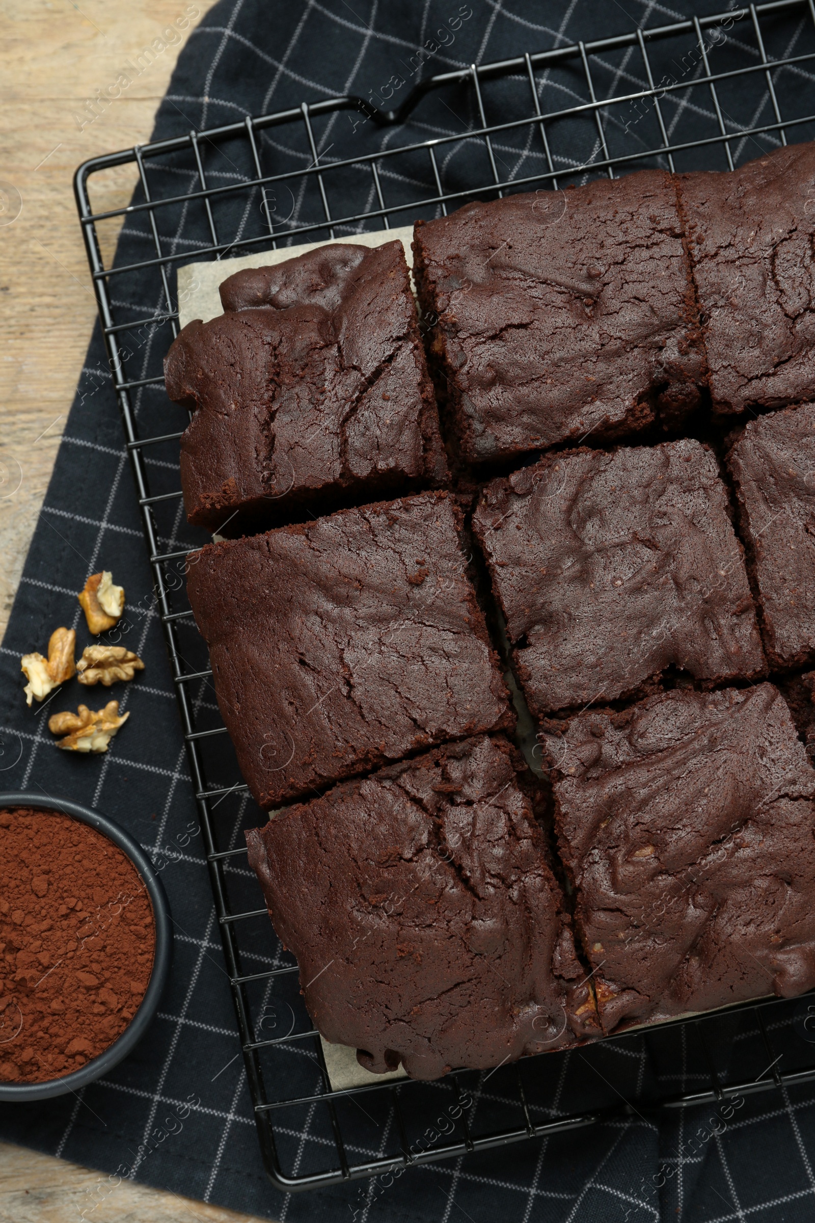 Photo of Delicious freshly baked brownies, cocoa powder and walnuts on wooden table, flat lay