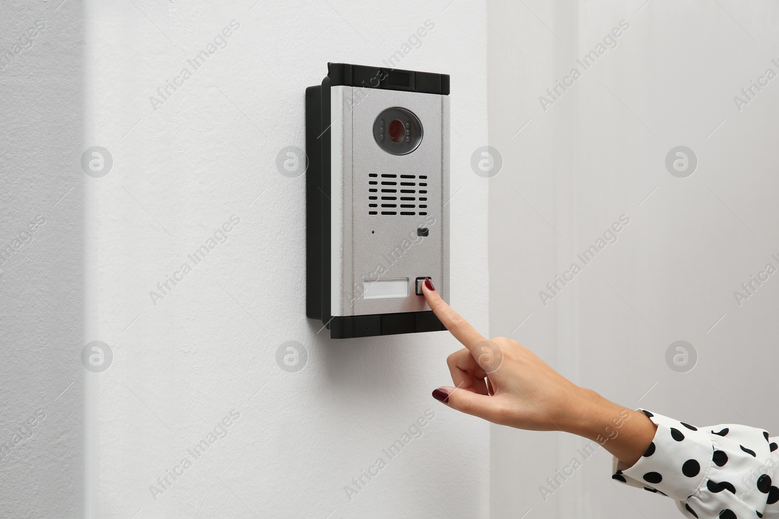 Photo of African-American woman ringing intercom with camera in entryway, closeup