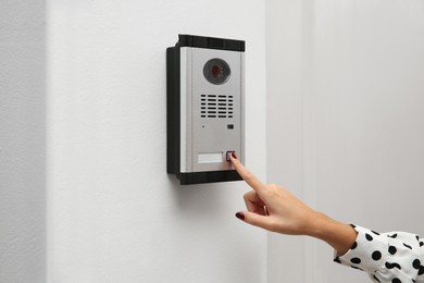 Photo of African-American woman ringing intercom with camera in entryway, closeup