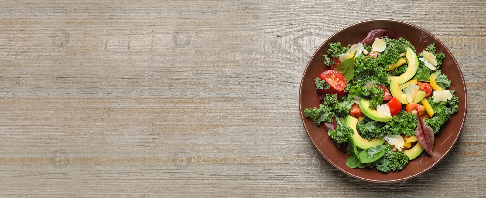 Image of Tasty fresh avocado salad and space for text on wooden table, top view. Banner design