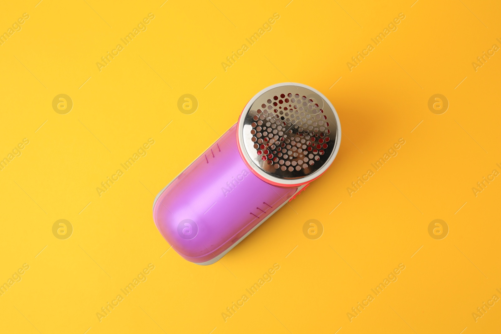 Photo of Modern fabric shaver on yellow background, top view