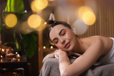 Spa therapy. Beautiful young woman lying on massage table in salon, space for text