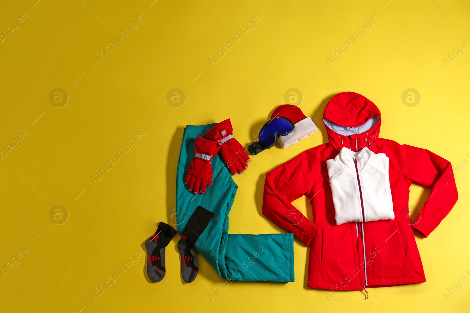 Photo of Stylish winter sport clothes on yellow background, flat lay