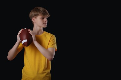 Teenage boy with american football ball on black background. Space for text