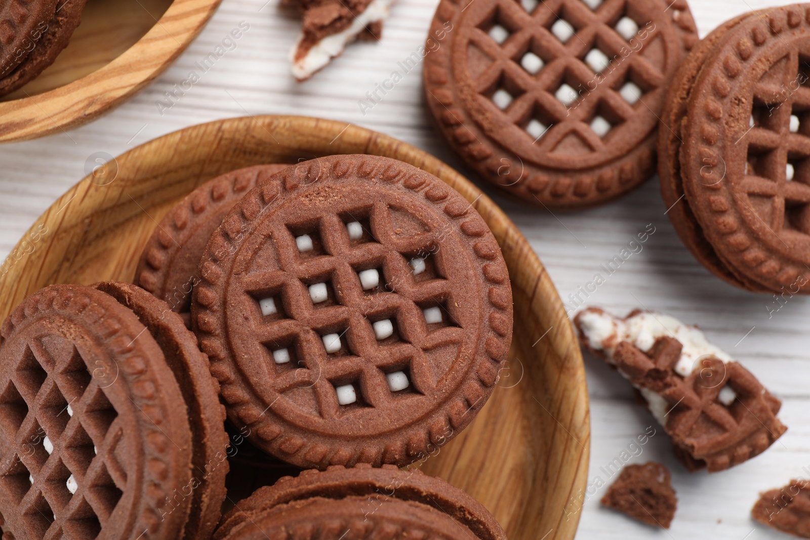 Photo of Tasty chocolate sandwich cookies with cream on white wooden table, flat lay