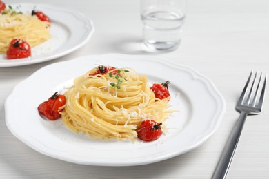 Tasty capellini with tomatoes and cheese served on white wooden table, closeup. Exquisite presentation of pasta dish