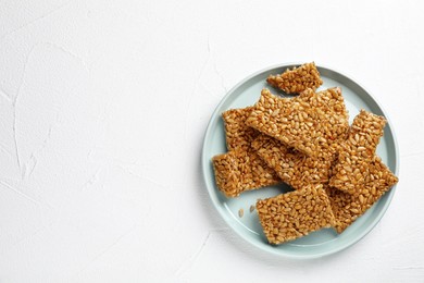 Photo of Plate with delicious kozinaki pieces on white table, top view. Space for text